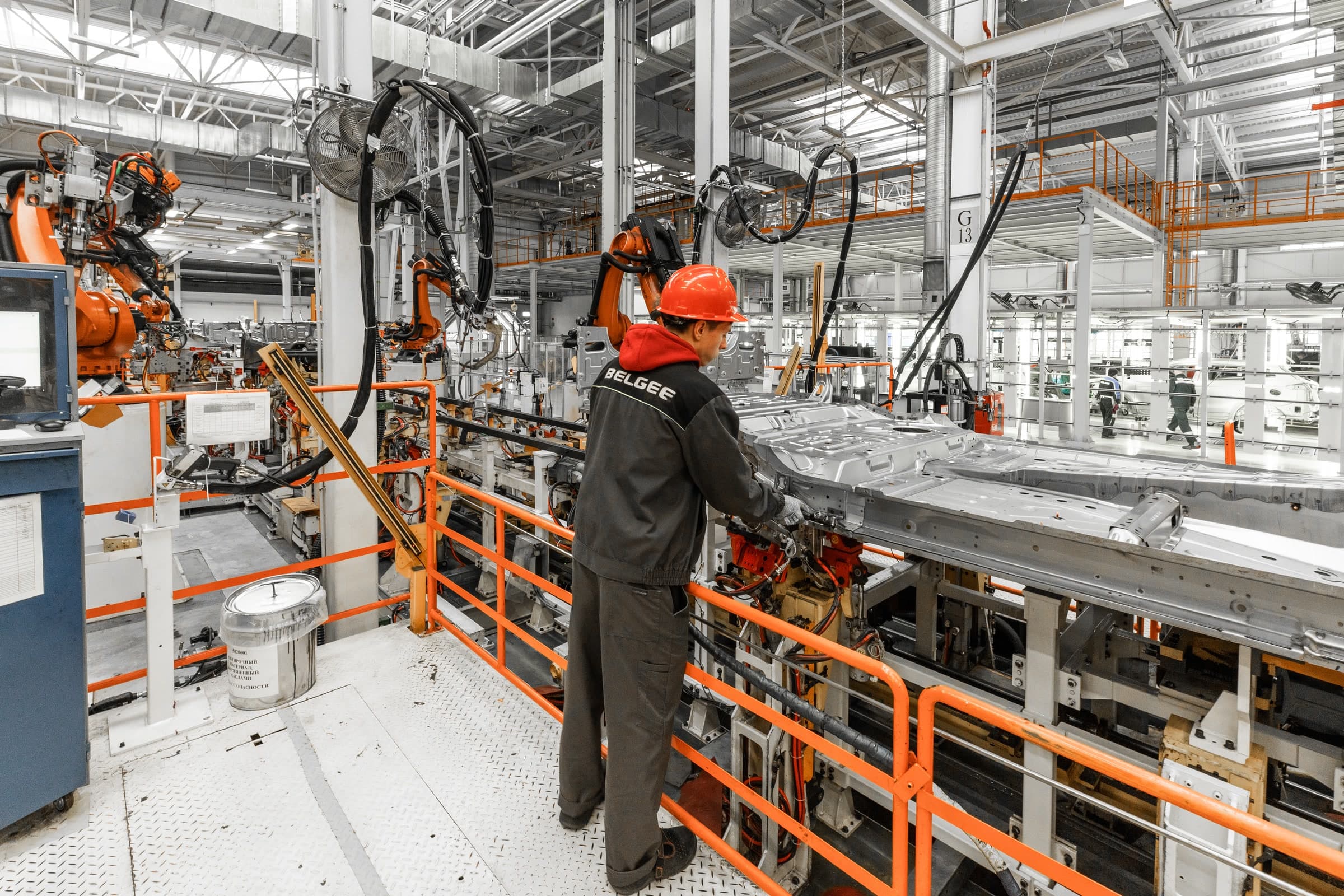 Mitarbeiter in einer automatisierten Fahrzeugproduktion mit Industrierobotern